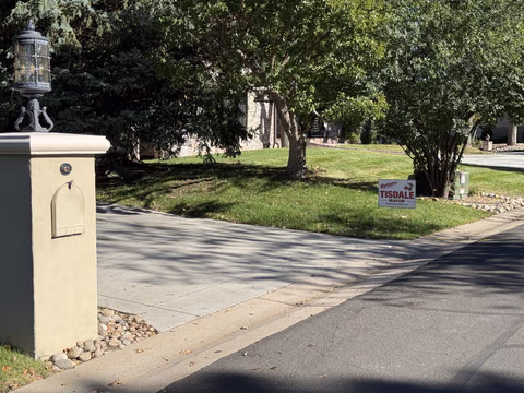 A Doug Tisdale sign in a shaded front yard.